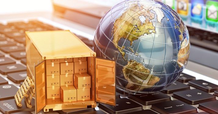 A miniature globe next to a miniature shipping container filled with cardboard shipping boxes sitting on a large keyboard.