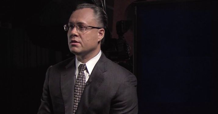 A man in a business suit speaking about factors for strategic global management.