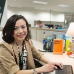 Supply chain grad Xuesi Li sits at her desk that's adorned with Michigan State University merch.