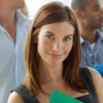 A woman smiling into the camera with other employees out of focus behind her.