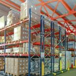 Warehouse in a distribution center filled with boxes and a forklift driving down the aisle.