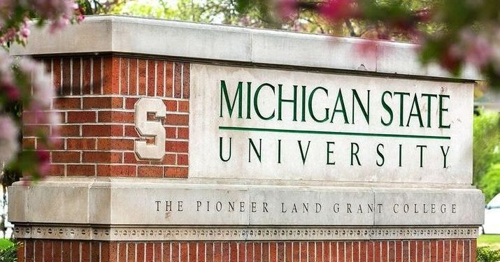 MSU brick sign that says in capital green letters "Michigan State University" and below that in smaller letters on a concrete slab it says "The Pioneer Land Grant College".