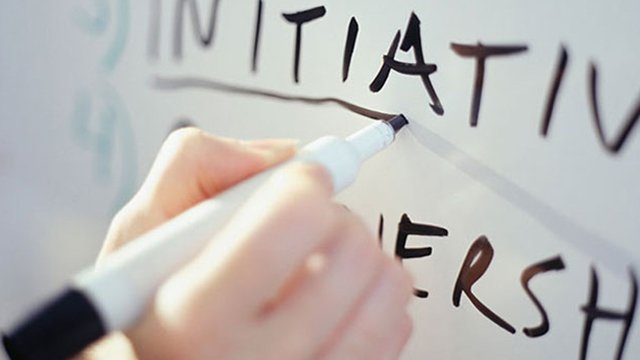 Close up of a hand writing out leadership skills on a whiteboard with a black dry erase marker.