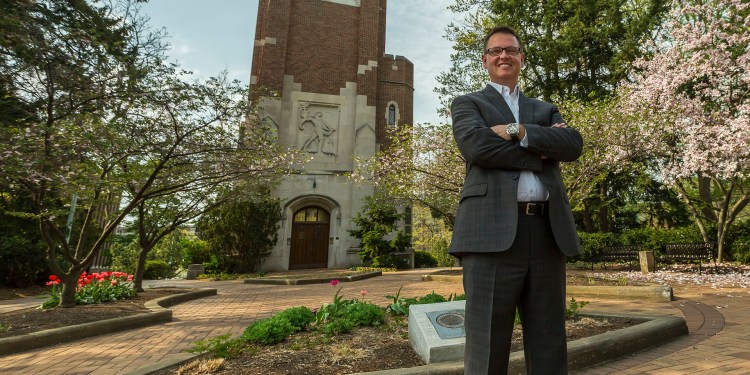 Jeff Day, MS in Management, Strategy and Leadership grad, standing in a business suit on MSU's campus.