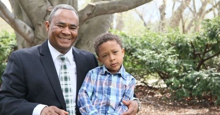 Albertus Kariko, graduate of MSU's MS in Management, Strategy and Leadership degree, sitting with his son on campus at MSU.