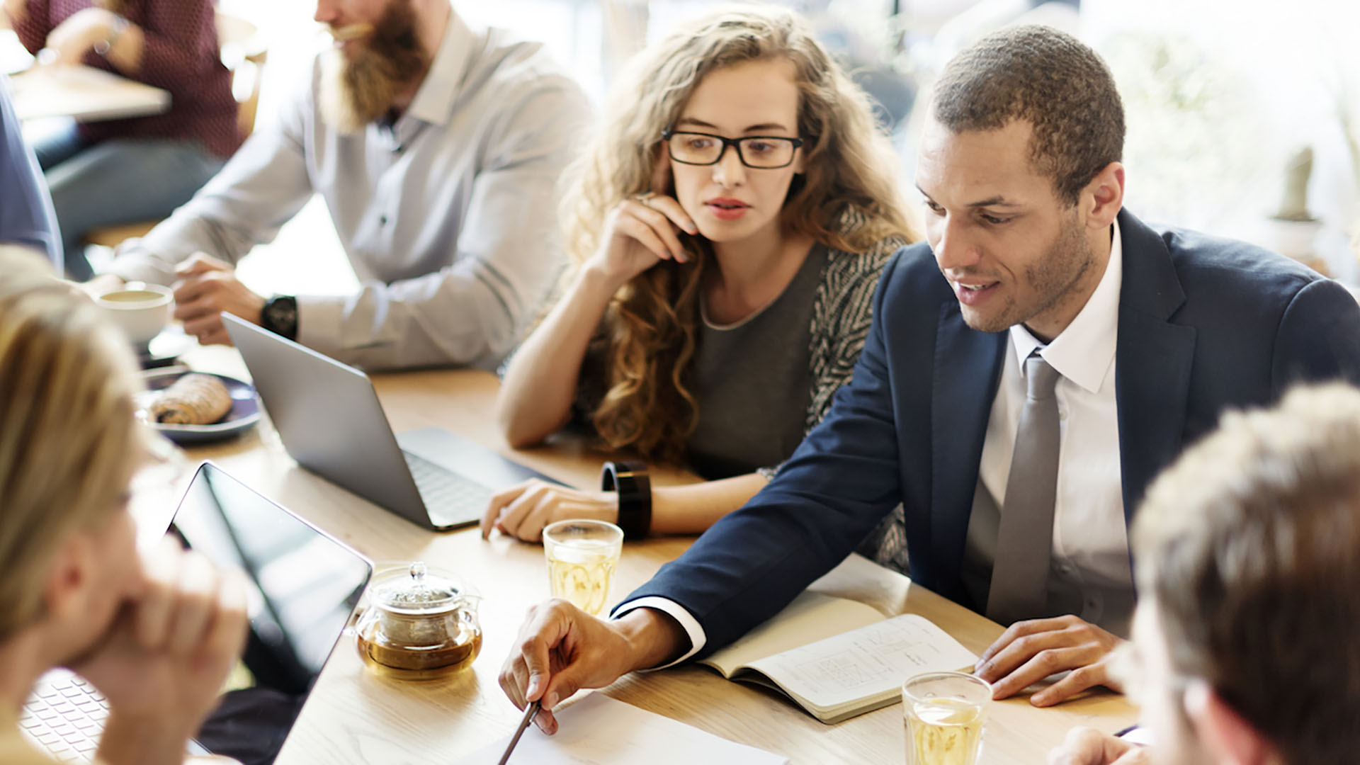 Business man discussing strategic management with others around a table at a coffee shop.