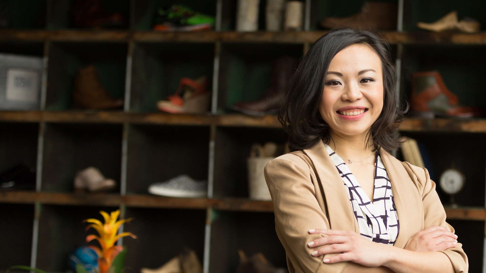 Supply chain grad Xuesi Li standing in front of a wall filled with shoes, smiling at the camera.