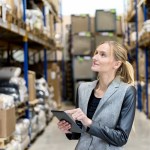 Female distribution manager reviewing digital tablet at warehouse.