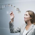 A female human resources manager looking at different profile pictures on futuristic digital touchscreen light-board