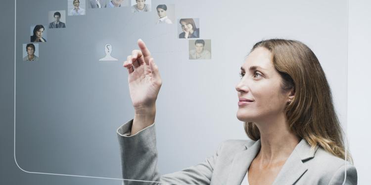 A female human resources manager looking at different profile pictures on futuristic digital touchscreen light-board