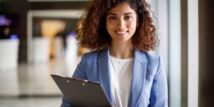 Young female human resources specialist holding a clipboard.