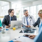 Team of doctors and healthcare managers communicating while having a meeting at doctor's office in the hospital.