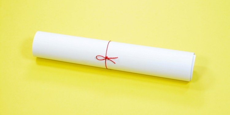 Rolled accreditation document tied with red string on yellow background.