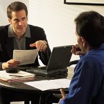 Two men discussing business across a table.