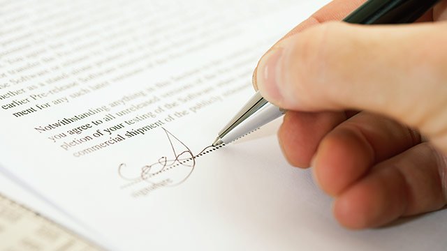 A pen signing the signature line on a contract.