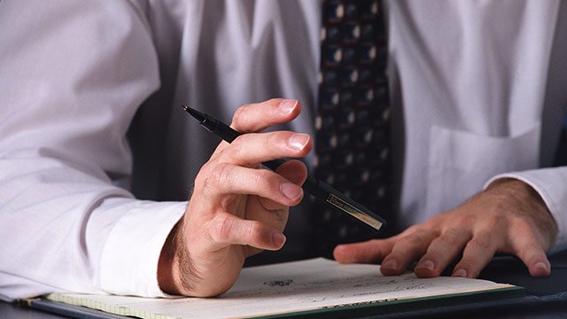 A pair of hands holding a pen writing on a piece of paper.