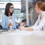 HR Coaching concept. An older businesswoman coaches a younger businesswoman in an office setting.