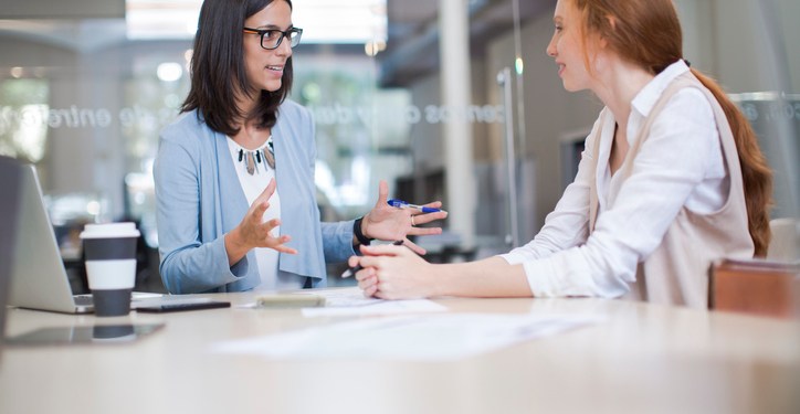 HR Coaching concept. An older businesswoman coaches a younger businesswoman in an office setting.