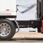 A semi-truck with a red cab and a white trailer.