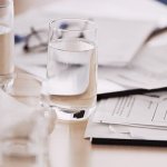 A table with glasses of water and paper with graphs on them.