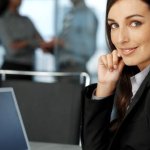 A woman dressed in a suit working on her computer.