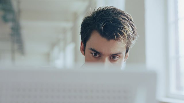 A young man on a computer in a computer lab.