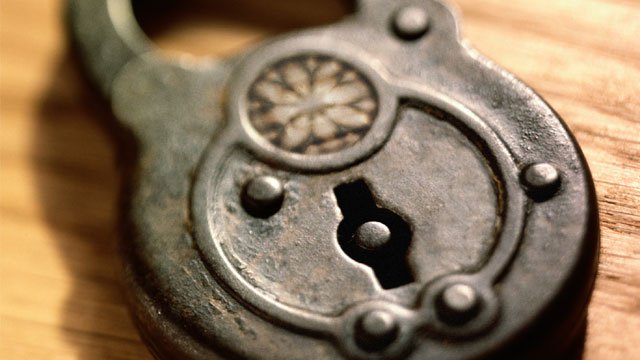 An old, antique lock sitting on top of a wooden table.