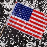 A small American flag sitting among small pieces of white confetti.