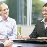 A group of three business professionals talking at a table.