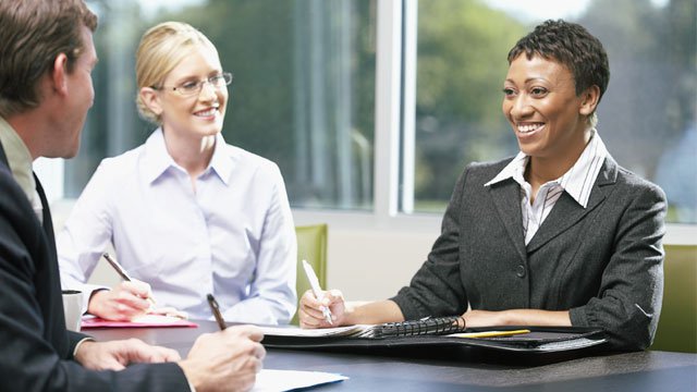 A group of three business professionals talking at a table.