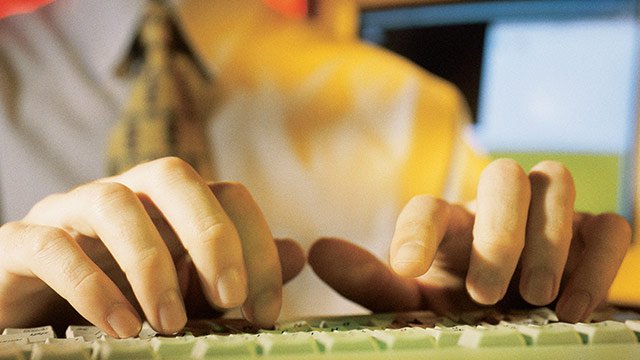 A set of hands typing on a white keyboard.