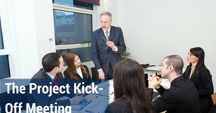 Employees in a conference room listening to a man standing up and talking.