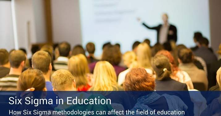 A room full of students listening to a six sigma professor giving a lecture in front of a projection screen.