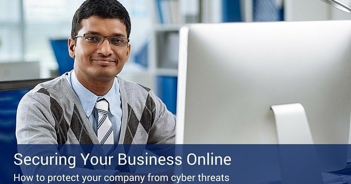 A man sitting at a computer with a blue sign on the bottom on the picture that says "Securing Your Business online".