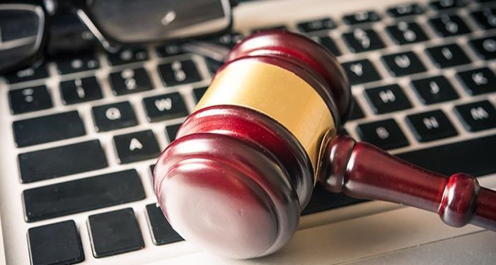 A computer keyboard with eye glasses and a judge's gavel sitting on top of it.