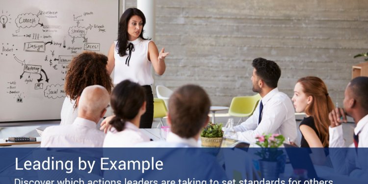 A woman standing in front of a whiteboard with drawings and concepts giving a presentation about leadership.