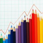 Illustrated line graph following a trend line on top of a row of colored pencils against graph paper.