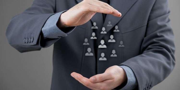 Man in a suit with his hands held part in the shape of a circle, with holographic images of people between his hands.