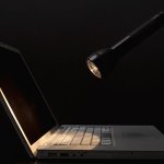 A flashlight shining on a laptop in a dark room.