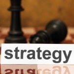 A chessboard with chess pieces scattered across the board and a white piece of paper on it that says strategy.