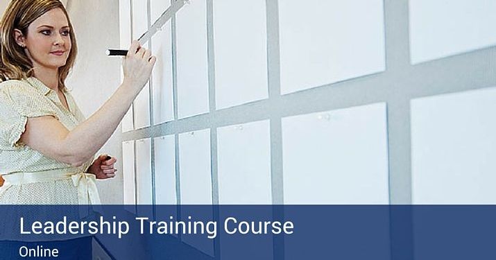 White pieces of paper hung up on a wall with a woman writing on them, preparing to start a leadership training course.