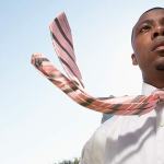 A man in a white dress shirt with his tie blowing in the wind.