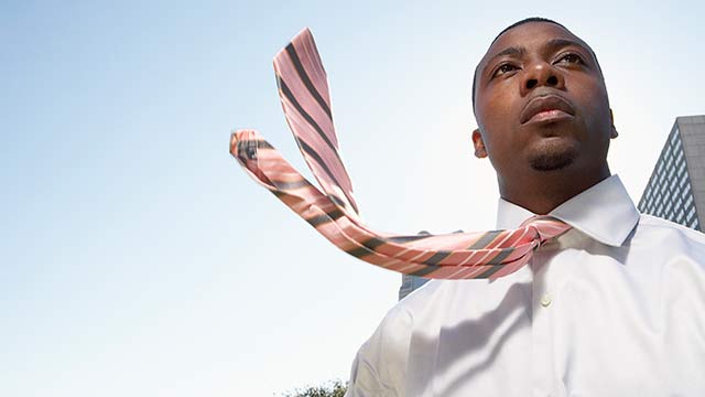 A man in a white dress shirt with his tie blowing in the wind.