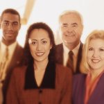 A group of six co-workers standing together, smiling into the camera after receiving their six sigma black belt certifications.