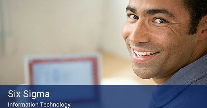 A man at a desk with his laptop looking back over his shoulder at the camera, with a blue banner on the botom of the image that reads "Six Sigma - information technology" in large white letters.