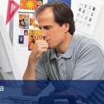 A man sitting down at a computer with his hand on his chin as if he is thinking, below him is a blue banner with white letters that reads "Six Sigma - Training".