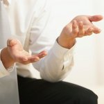 A partial shot of a businessman wearing a suit and gesturing with his hands while comparing six sigma and lean six sigma.