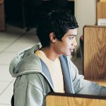 A student sitting at a computer in a computer lab with privacy desks.