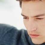 A man in a charcoal colored turtleneck sweater looking away from the camera.