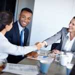 HR Business Partner depicted as a businessman joined by two business women shaking hands across a table.